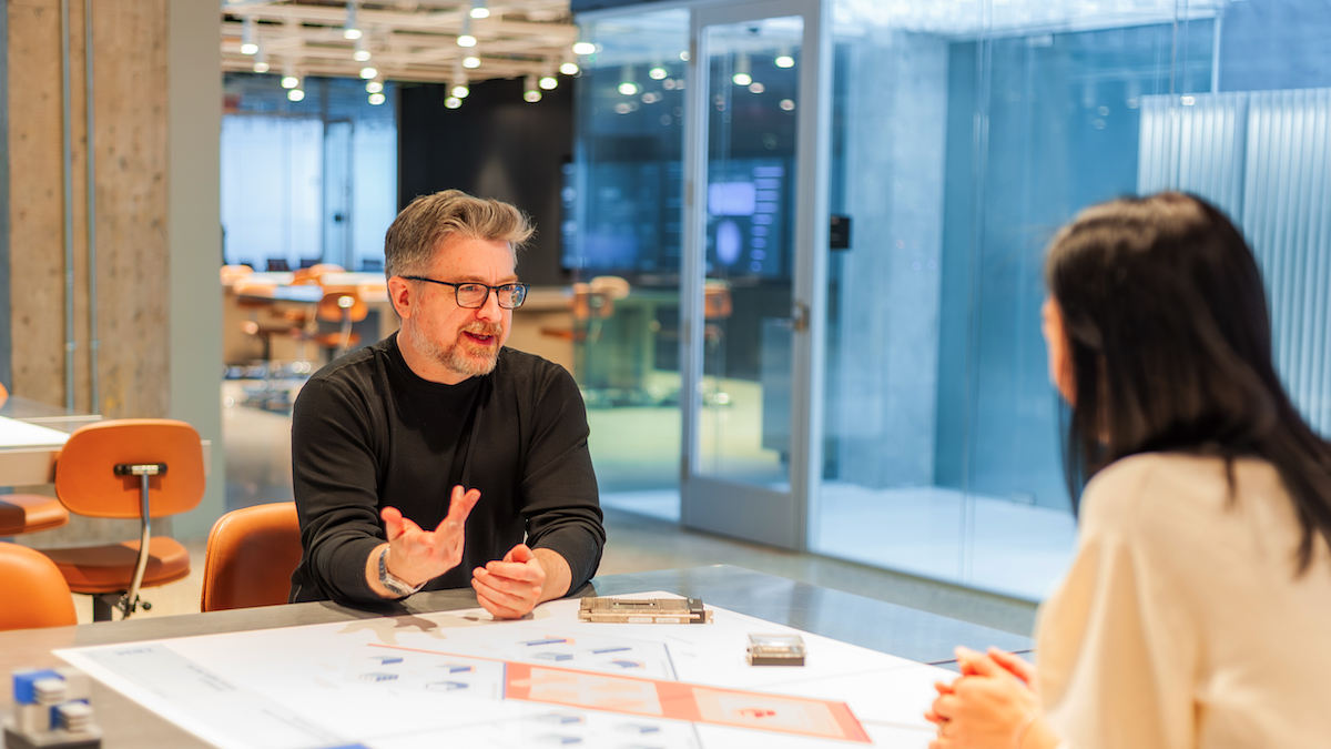 David Cox is pictured during a discussion in a glass-walled office, aligned with themes of open-source innovation and teamwork.