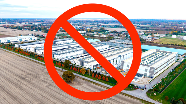 Aerial view of a large data center with a red prohibition sign overlayed, indicating opposition.