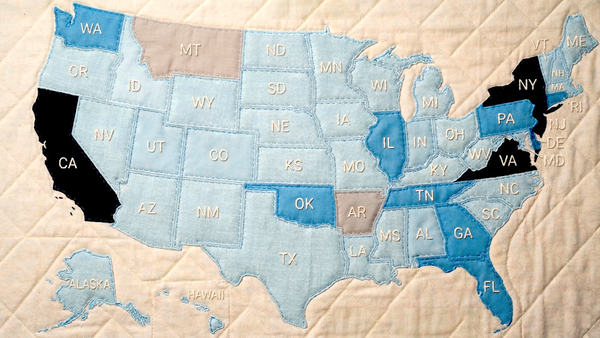 Quilt map of U.S. states with varying shades, some states in black, illustrating AI legislation differences.